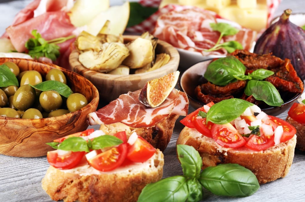 Italienisches Antipasti-Weinhäppchen-Set. Käsesorten, mediterrane Oliven, Essiggurken, Prosciutto di Parma, Tomaten, Artischocken